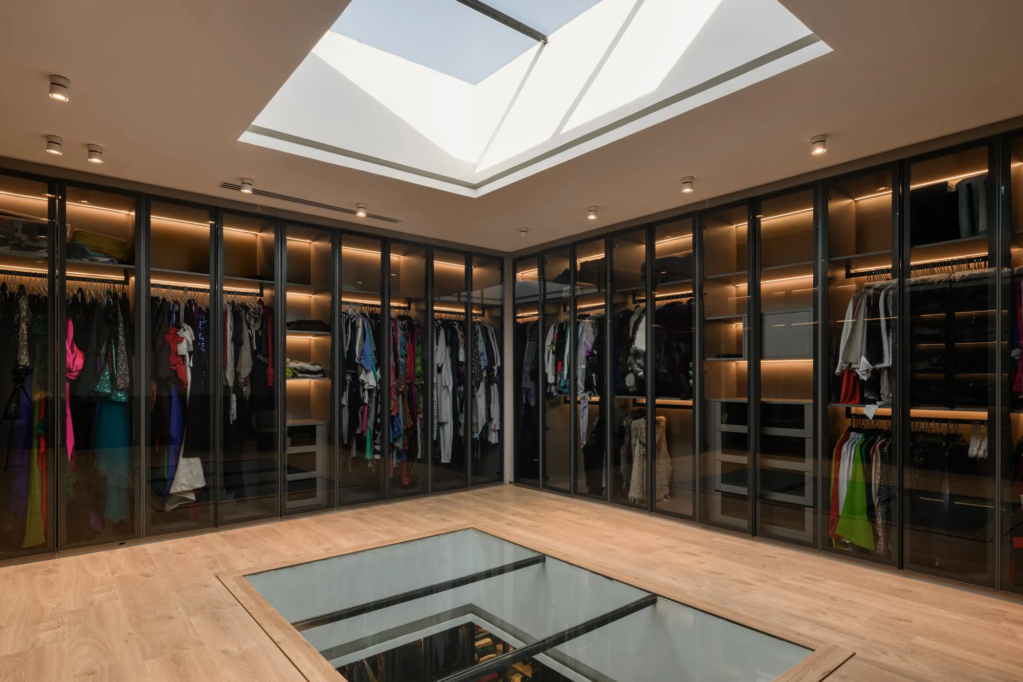 Lit glass wardrobes lining a walk-in closet, Palm Hills Residence